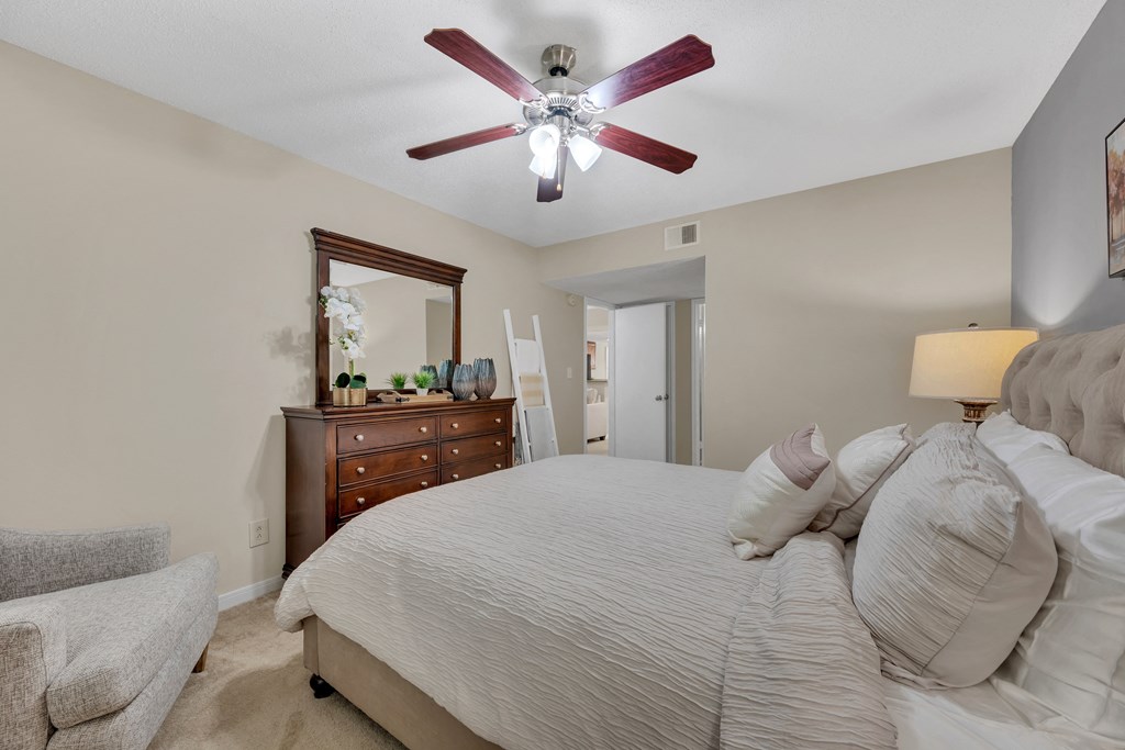the master bedroom has a large bed and a ceiling fan